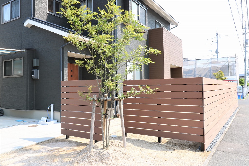 木目調の横板フェンスの手前にシンボルツリーを植えた目隠しの施工例