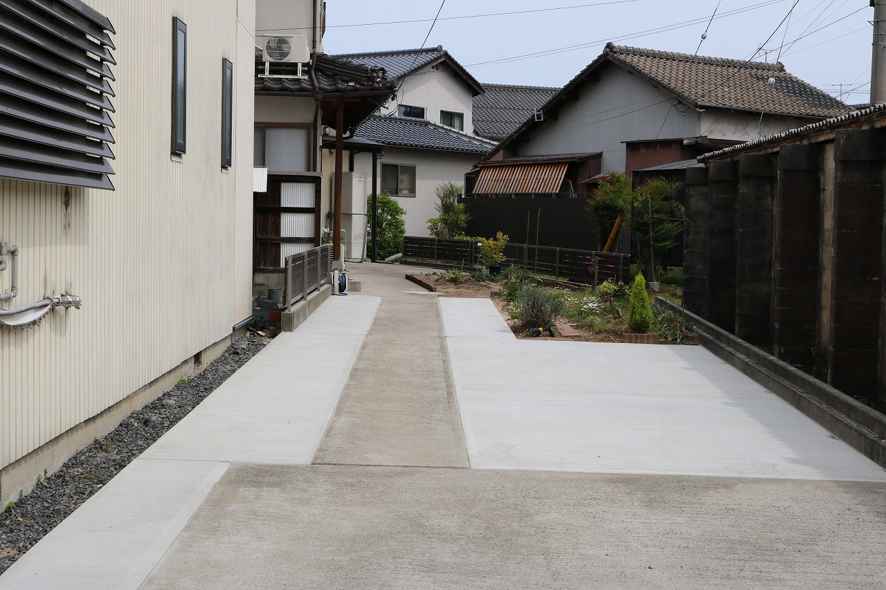 細長い敷地に土間コンクリートの駐車スペースと植栽帯を並べた施工例