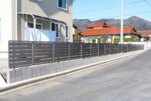 道路沿いに板のすき間を取った横格子の目隠しフェンスを設けた施工例