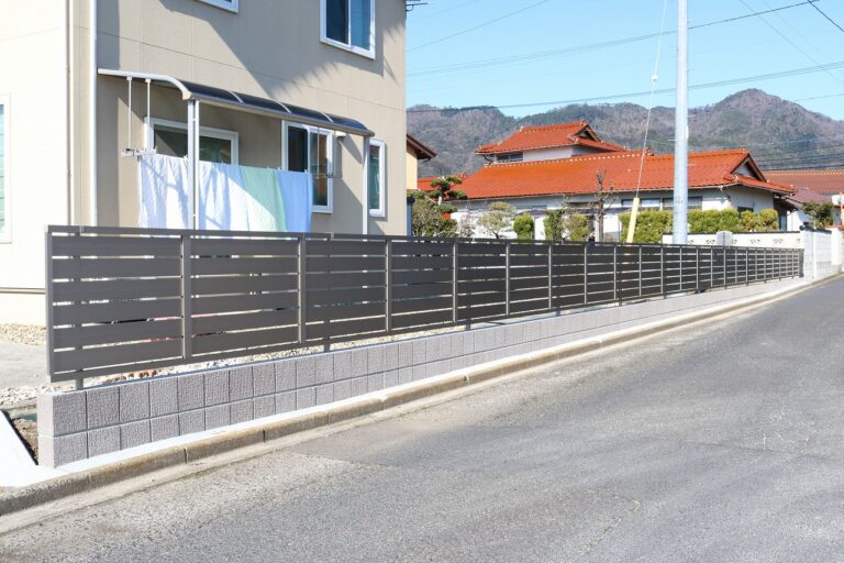 道路沿いに板のすき間を取った横格子の目隠しフェンスを設けた施工例