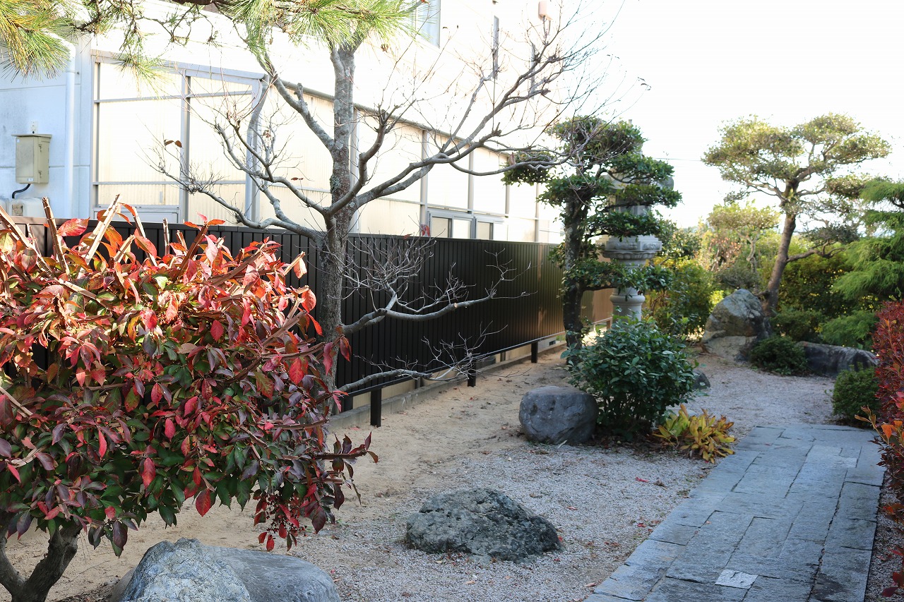 紅葉した庭木と刈り込みの緑、石張りの園路を組み合わせた庭の施工例