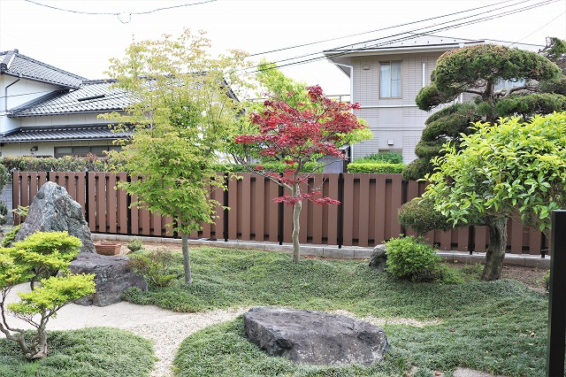 モミジと低木、庭石を配し、木調フェンスで囲った庭の施工例