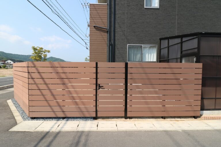 木目調の横板張り目隠しフェンスと開き戸のある住宅の外構