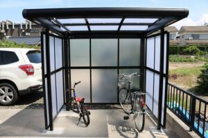 ポリカーボネート製の側面パネルを備えたカーポートに自転車と車が置かれている様子