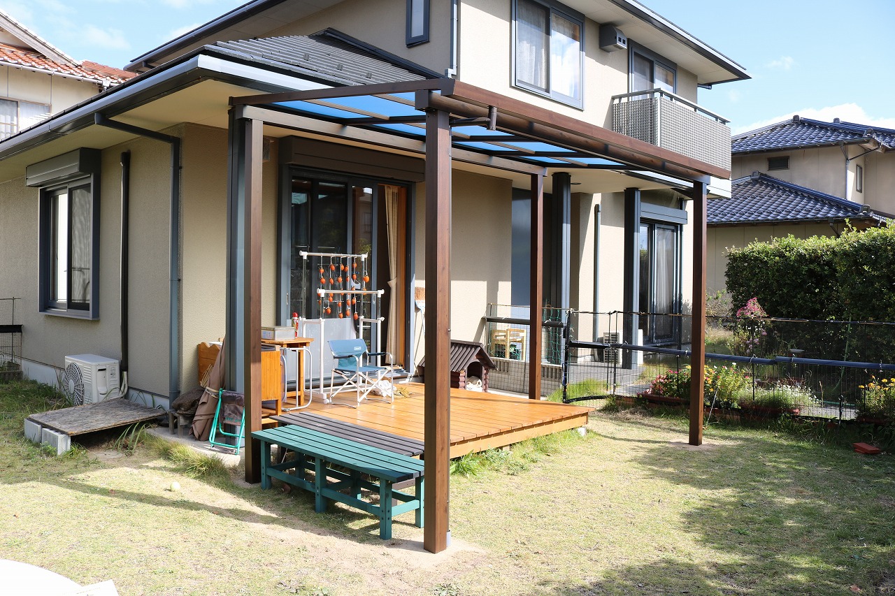 二階建て住宅の壁面に沿って長く伸びる白い手すり付きの木調ウッドデッキ