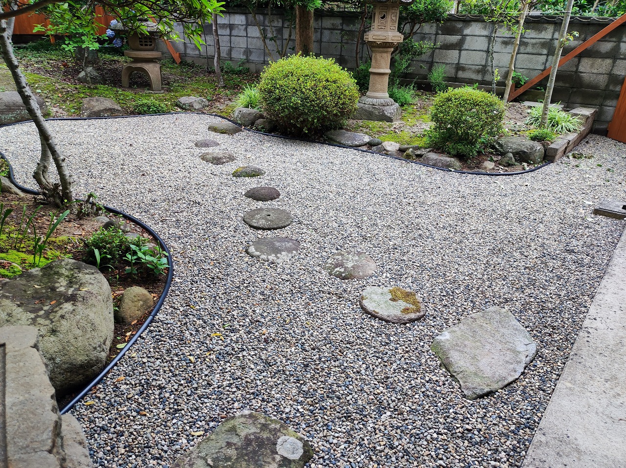 玉砂利敷きの坪庭に飛び石と刈り込まれた低木を配した施工例