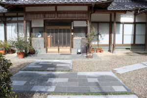 石張りのアプローチと植木鉢を配した和風住宅の玄関まわり