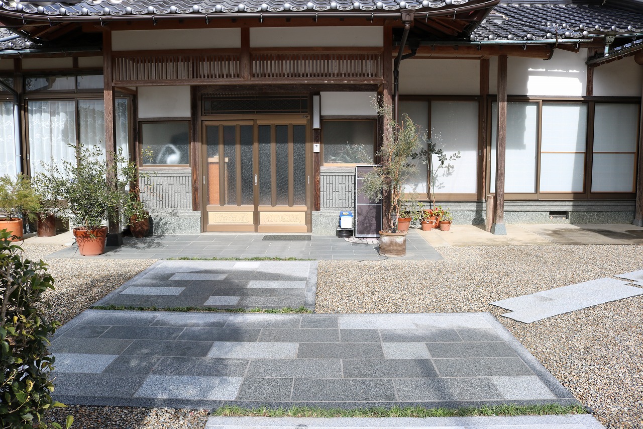石張りのアプローチと植木鉢を配した和風住宅の玄関まわり
