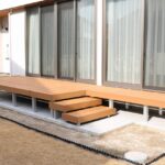 松江でつくる、庭とつながるウッドデッキのある暮らし リビングの掃き出し窓に沿って広がるL字型の人工木ウッドデッキと階段