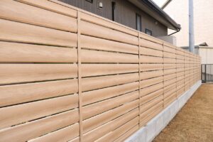 木目調のアルミ形材を使った横板ルーバーの目隠しフェンス、住宅の外壁沿いに設置された施工例