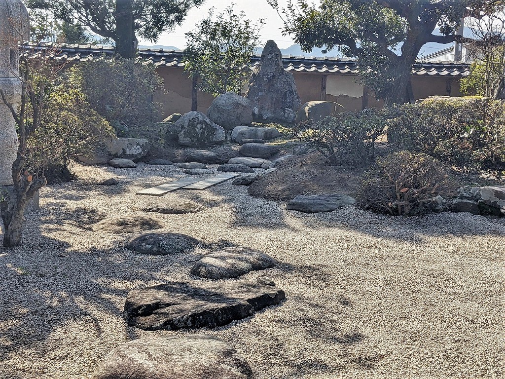 玉砂利と大小の石、剪定された低木を組み合わせた坪庭風の植栽