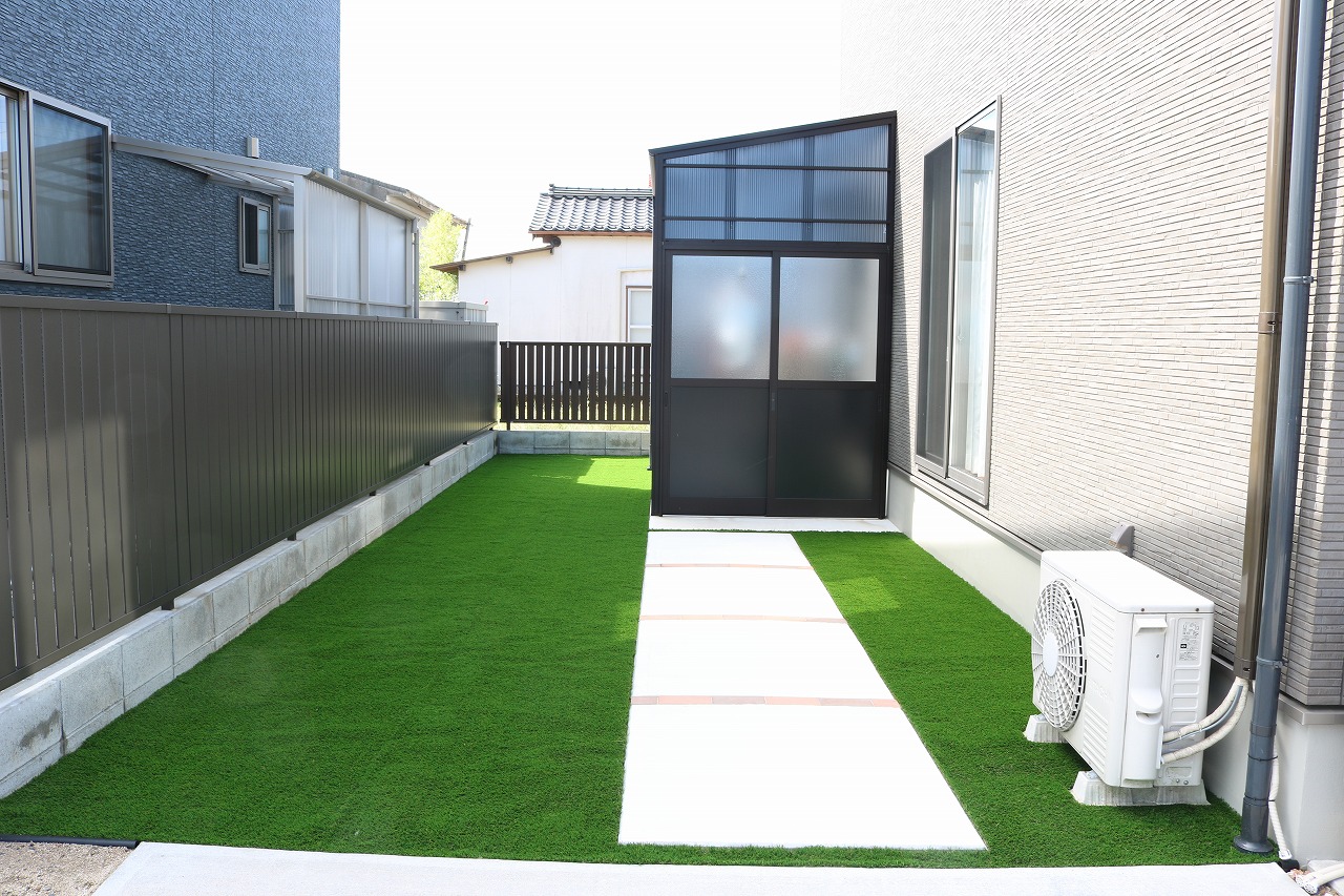 隣家との間に高さのある目隠しフェンスを立て、人工芝を敷いた細長い側庭の施工例
