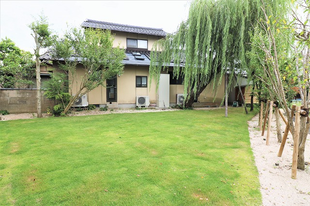 広い芝生の庭に複数の樹木を配した住宅の植栽全景