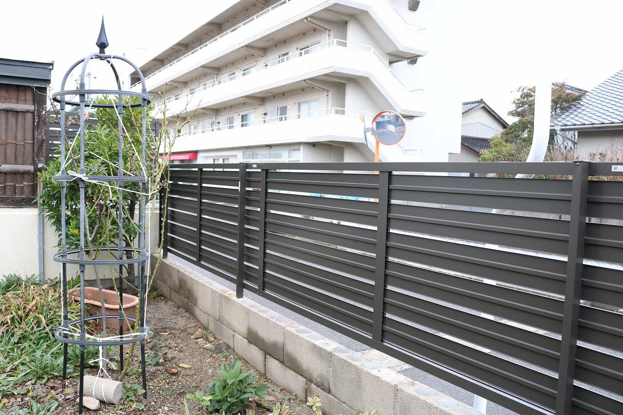 横板を隙間を空けて配置した目隠しフェンスと、オベリスクを添えた植栽
