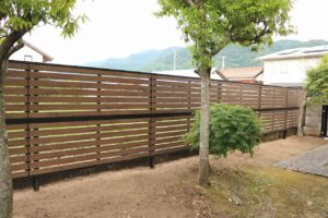 庭木の緑に囲まれた木調の横板目隠しフェンスの施工例