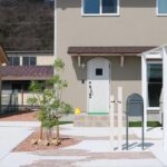 松江でつくる、雨の日も気持ちが軽くなるカーポートのある暮らし 玄関のすぐ横に設けた白いカーポートと、植栽やポストを配したアプローチの施工例