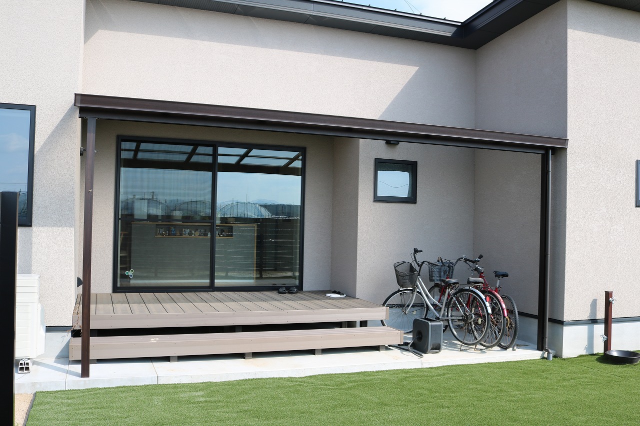 人工芝の庭に面した屋根付きウッドデッキの施工例